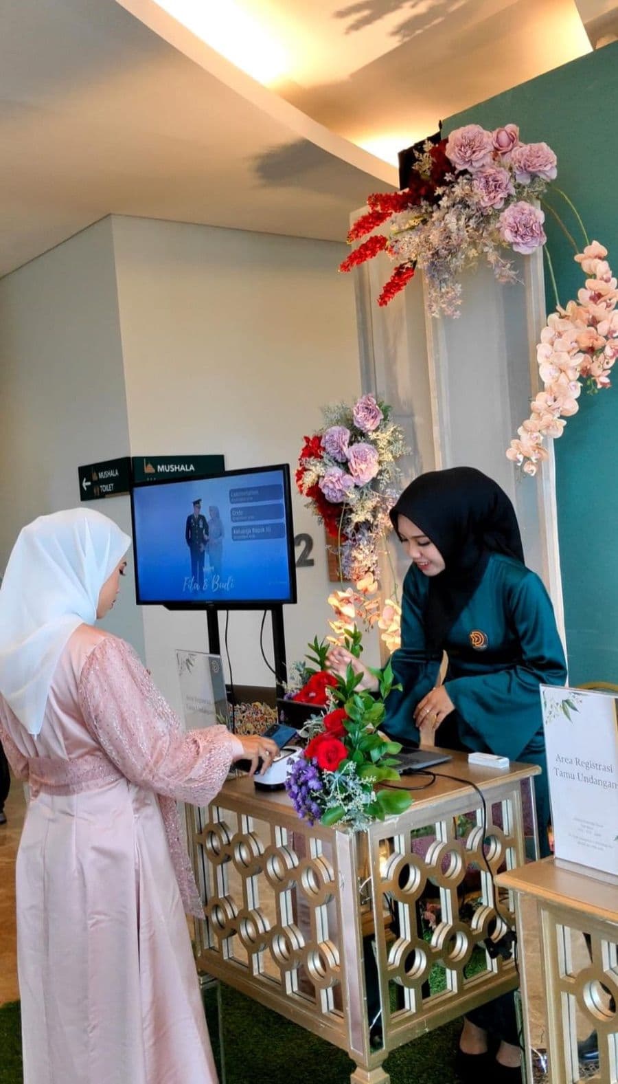 A guest scans her invitation QR code at the registration desk, with the guest list on screen